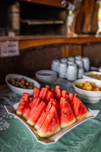 a plate of watermelon on a table with bowls of nuts at Parque Llanquihue - Héroes Parques in Llanquihue