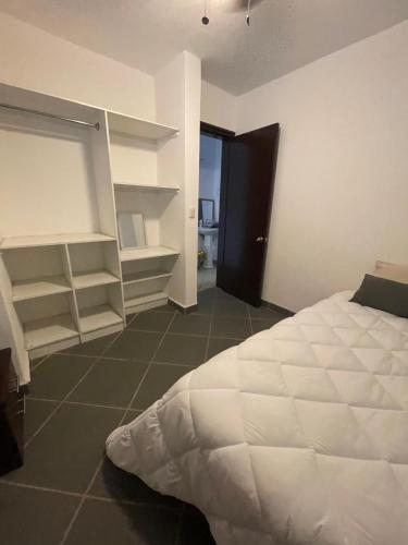 a bedroom with a white bed and open shelving at Bonita casa en Oaxaca in Oaxaca City