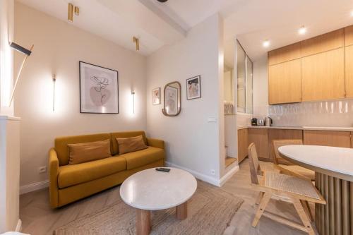 un salon avec un canapé et une table et une cuisine dans l'établissement Elegant 4-Star stay in central Paris - Suite Apart, à Paris