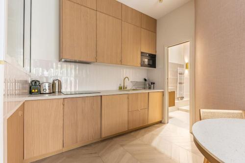 une grande cuisine avec des placards en bois et une table dans l'établissement Elegant 4-Star stay in central Paris - Suite Apart, à Paris