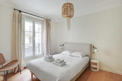 une chambre blanche avec un lit avec des serviettes dessus dans l'établissement Authentic apartment - 3BR-8P - Clignancourt, à Paris