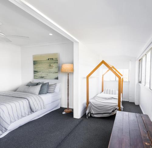 a white bedroom with two beds and a mirror at Finns at Old Bar in Old Bar