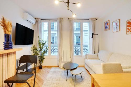 un salon avec un canapé et deux fenêtres dans l'établissement Charming Apartment - 1B-4P - Sacré Coeur, à Paris