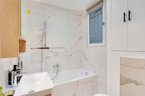 une salle de bain blanche avec un lavabo et une douche dans l'établissement Charming Apartment - 1B-4P - Sacré Coeur, à Paris