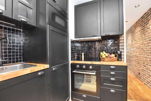 - une cuisine avec des placards noirs et un évier dans l'établissement Magnificent apartment- 2BR-6P - Republique, à Paris