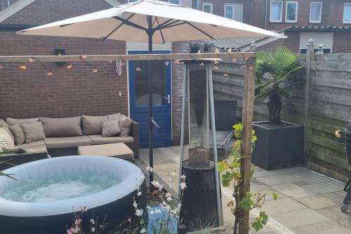 a hot tub in a backyard with an umbrella at Garden, Jacuzzi, bbq, city centre, 2 bedrooms in Alkmaar