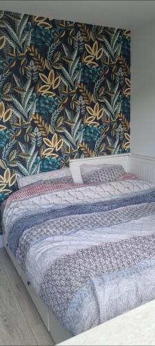 a bed in a bedroom with a floral wallpaper at Garden, Jacuzzi, bbq, city centre, 2 bedrooms in Alkmaar