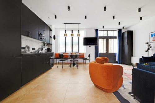 Il comprend un salon avec une chaise orange et une cuisine. dans l'établissement Elegant apartment - 3BR-7P - Moulin Rouge, à Paris