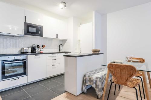 une cuisine avec des armoires blanches et une table et des chaises dans l'établissement Classy appartement - Flea Market, à Saint-Ouen