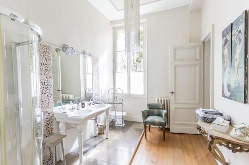 une salle de bain blanche avec un lavabo et un miroir dans l'établissement Château Couffins, à Asques