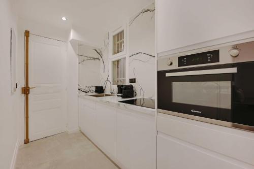 - une cuisine blanche avec un four micro-ondes et un comptoir dans l'établissement Charming apartment - 2BR-6P - Gare Saint-Lazare, à Paris