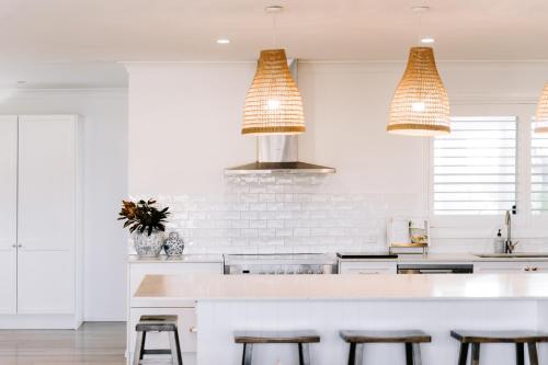 a kitchen with white walls and a counter with stools at Finns at Old Bar in Old Bar