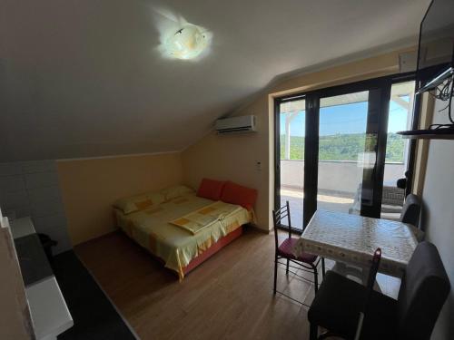 a bedroom with a bed and a table and a window at Apartments Mudrić in Herceg-Novi
