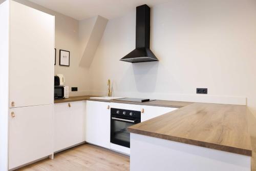 une cuisine avec des armoires blanches et un four à plaques de cuisson dans l'établissement Cosy apartment - 4BR-12P - Canal Saint-Martin, à Paris