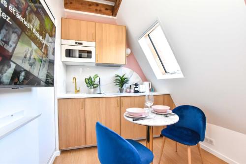une petite cuisine avec une table et des chaises bleues dans l'établissement Charming studio - 2P - Champs Elysées, à Paris