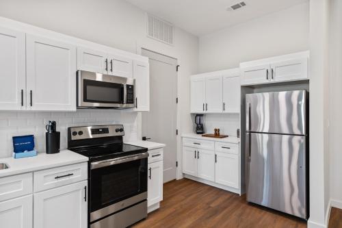 a kitchen with white cabinets and a stainless steel refrigerator at The Corbin 1204 - Magnolia Moderns in Fort Worth