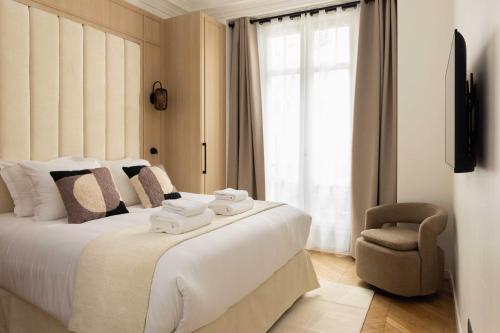 une chambre avec un grand lit blanc et une chaise dans l'établissement Cosy apartment - 3BR-6P - Montmartre-Sacré-Cœur, à Paris