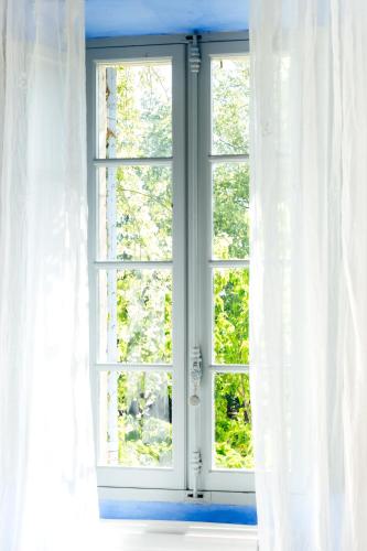 an open window with white curtains in a room at Bastide Rose in Le Thor