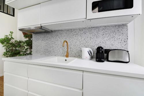 une cuisine blanche avec un évier et un micro-ondes dans l'établissement Charming apartment 2BR- 4P - Rochechouart, à Paris