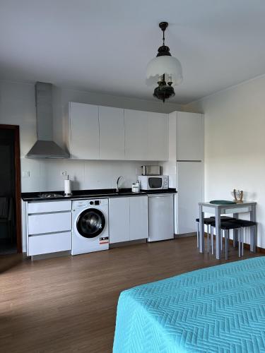 a kitchen with white cabinets and a washing machine at Quinta da Touça in Baião