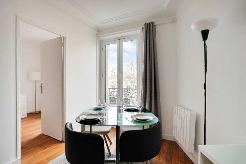 une salle à manger avec une table et une grande fenêtre dans l'établissement Chic apartment - 1BR-4P - Next to Paris, à Saint-Ouen