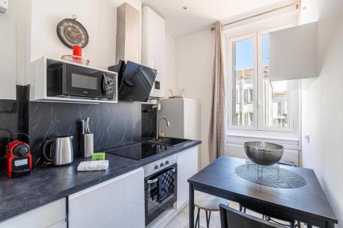 une petite cuisine avec une table et un micro-ondes dans l'établissement Cozy One Bedroom apartment - heart of Cannes, à Cannes