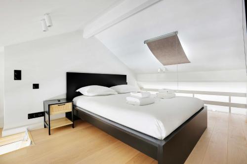 une chambre avec un lit avec des draps blancs et des oreillers dans l'établissement Charming air-conditioned apt for a cosy atmosphere, à Paris