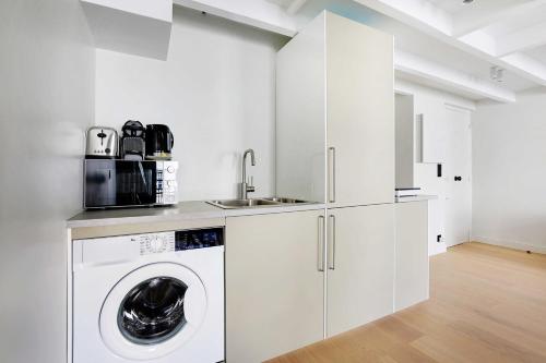 - une cuisine blanche avec un lave-linge et un évier dans l'établissement Charming air-conditioned apt for a cosy atmosphere, à Paris
