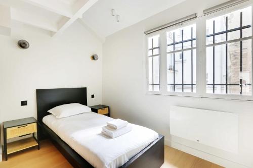 une chambre blanche avec un lit et une fenêtre dans l'établissement Charming air-conditioned apt for a cosy atmosphere, à Paris