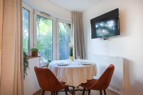 une table à manger avec des chaises et une télévision murale dans l'établissement Charming studio apartment for 2 - Bastille, à Paris
