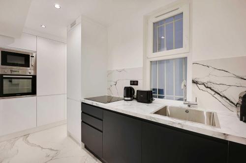 une cuisine blanche avec un évier et une fenêtre dans l'établissement Amazing Apartment - 2BR-6P - Gare Saint-Lazare, à Paris