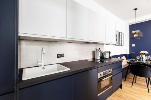 - une cuisine avec des placards bleus et blancs et un évier dans l'établissement Spacious Apartment- 2BR-6P - Porte Saint-Denis, à Paris