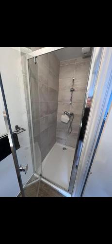 une douche avec une porte vitrée dans une salle de bain dans l'établissement Appart hotel La Molle, à Berre-lʼÉtang