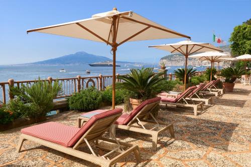 a row of chairs and umbrellas on a beach at Grand Hotel Royal in Sorrento