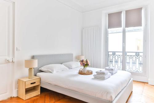 une chambre blanche avec un lit et une fenêtre dans l'établissement Spacious apt - 2BR-4P - Montmartre-Moulin Rouge, à Paris