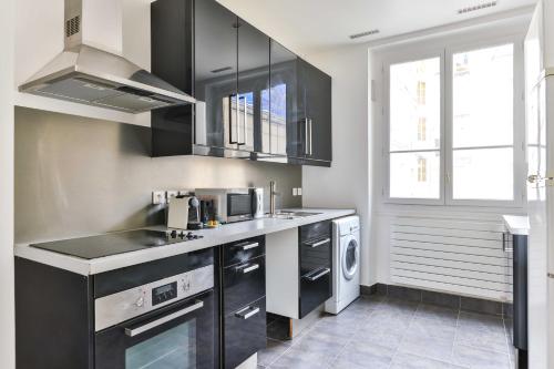 une cuisine avec des armoires noires et un lave-linge/sèche-linge dans l'établissement Spacious apt - 2BR-4P - Montmartre-Moulin Rouge, à Paris