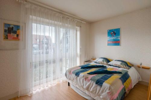 une chambre avec un lit et une grande fenêtre dans l'établissement Charming apartment with parking near Place Morny, à Deauville
