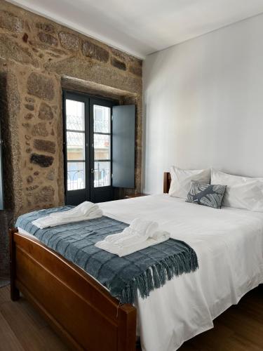 a bedroom with a large bed with a brick wall at Casa Dentro da Vila in Ponte de Lima