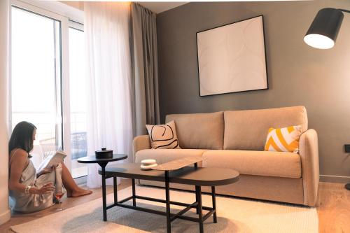 a woman sitting in a living room reading a book at Space Row Design Living in Heraklio Town