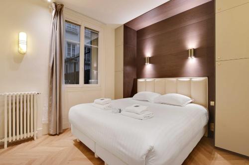 une chambre avec un grand lit blanc avec deux serviettes dans l'établissement Luxurious apartment - 2BR-6P - Saint-Germain, à Paris