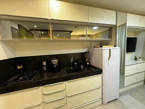a kitchen with white cabinets and a sink and a refrigerator at Get By Side - Jardim Oceania in Tambaú