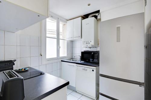 Elle comprend une petite cuisine avec des appareils électroménagers blancs et une fenêtre. dans l'établissement Peaceful apartment 2BR-4P - Arc de Triomphe, à Paris