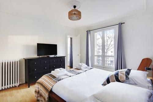 - une chambre avec 2 lits, une télévision et une fenêtre dans l'établissement Peaceful apartment 2BR-4P - Arc de Triomphe, à Paris