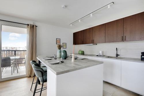 une cuisine avec des placards blancs et un comptoir avec des chaises dans l'établissement Magnificent apartment- 3BR-8P-Proche de la Seine, à Clichy