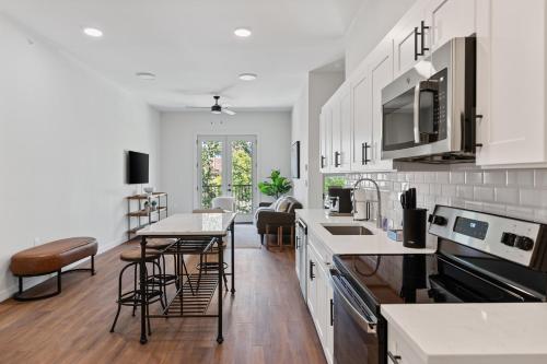 a kitchen with white cabinets and a table and chairs at The Corbin 1205 - Cowtown Urban Oasis in Fort Worth