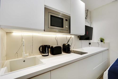 - une cuisine blanche avec un four micro-ondes au-dessus d'un évier dans l'établissement Studio ideally located in the heart of Paris, à Paris