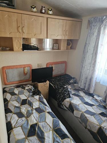 two beds in a small room with cabinets at the chase in Ingoldmells
