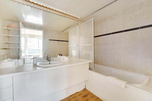 La salle de bains blanche est pourvue d'un lavabo et d'une baignoire. dans l'établissement Family Seine & Spacious Flat 8min walk to EiffelTower AC, à Paris