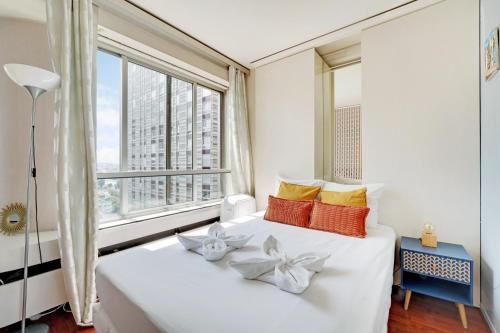 Cette chambre comprend un lit blanc et une grande fenêtre. dans l'établissement Family Seine & Spacious Flat 8min walk to EiffelTower AC, à Paris