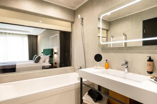a bathroom with a sink and a mirror and a bed at Empire Balneo & Spa Hotel in Hisarya